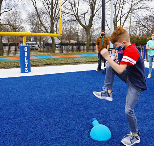 Child stomping on a cannon blaster to launch a ball between field goal posts.